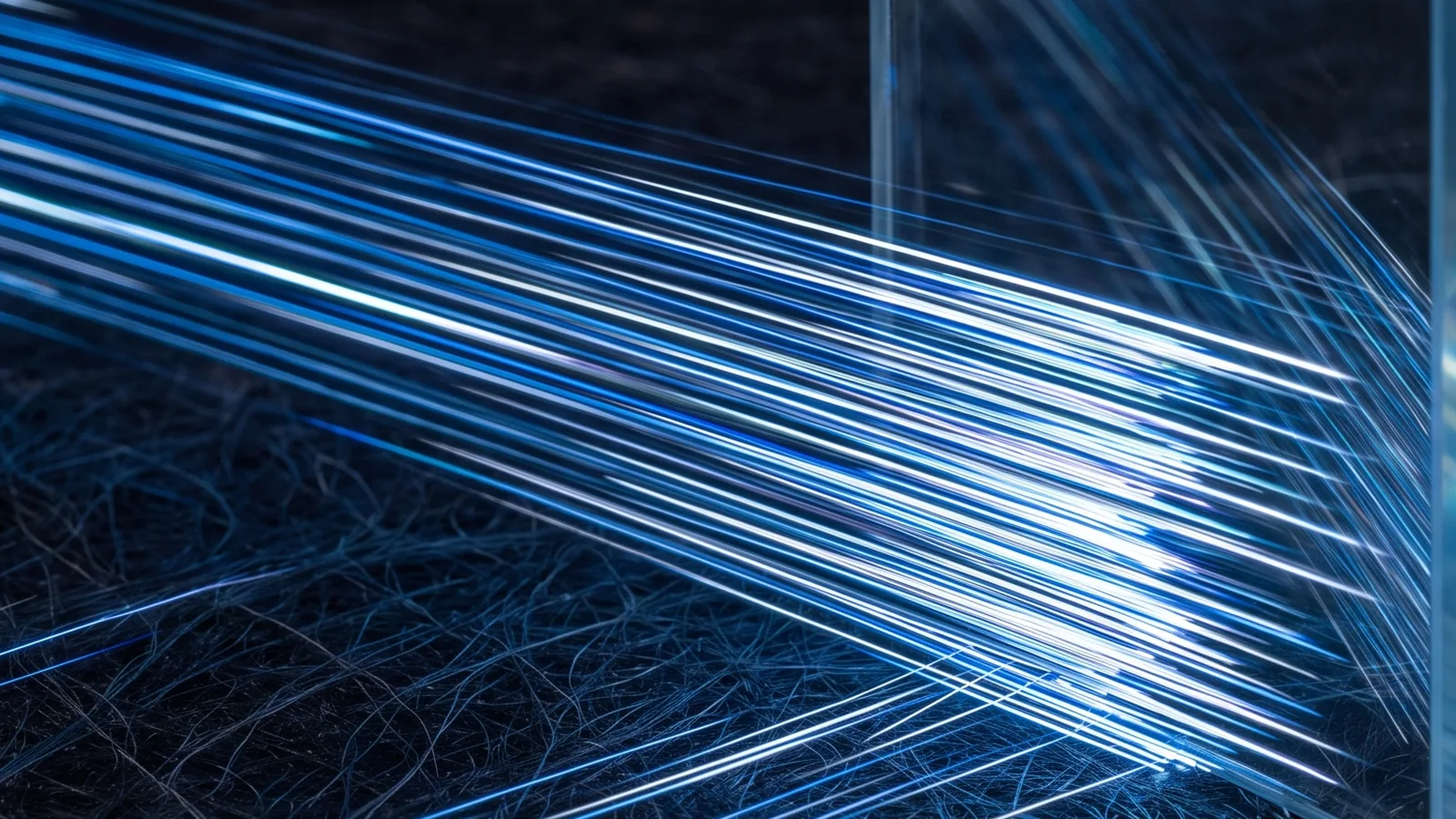 Dozens of parallel blue laser beams racing low across a dark fibrous surface and striking the edge of a thick glass wall.
